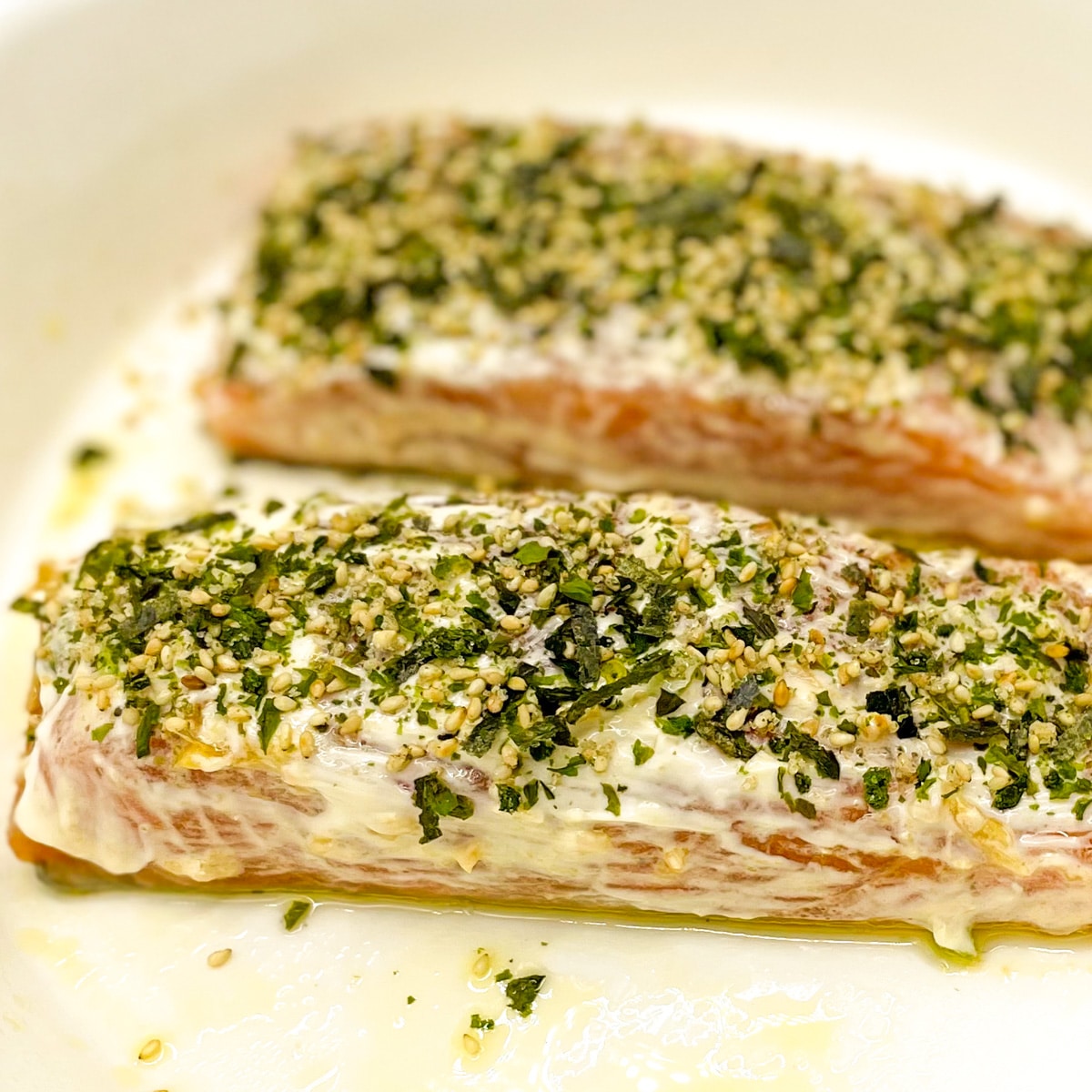 Two salmon fillets coated in mayonnaise with furikake seasoning sprinkled over top