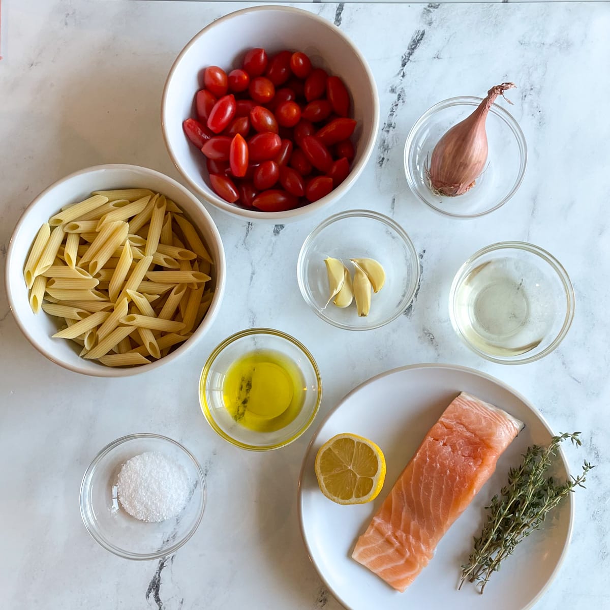 The ingredients for Penne al Salmone are shown on a white marble counter.