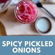 Pickled red onions are shown in a glass jar with a wooden cutting board, lid, and fork in the background.