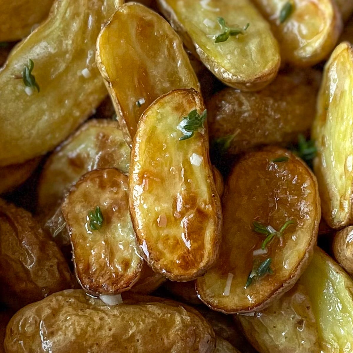 Closeup of fingerling potatoes roasted in air fryer coated in olive oil, lemon juice, garlic, and thyme dressing.