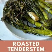 Roasted tenderstem broccoli and garlic are shown on a white plate; recipe is labeled with its title and the URL for Two Cloves Kitchen.