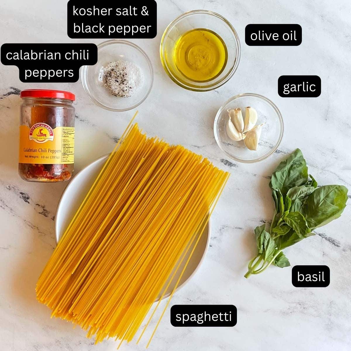 The labeled ingredients for Aglio Olio e Peperoncino sit on a white marble counter.