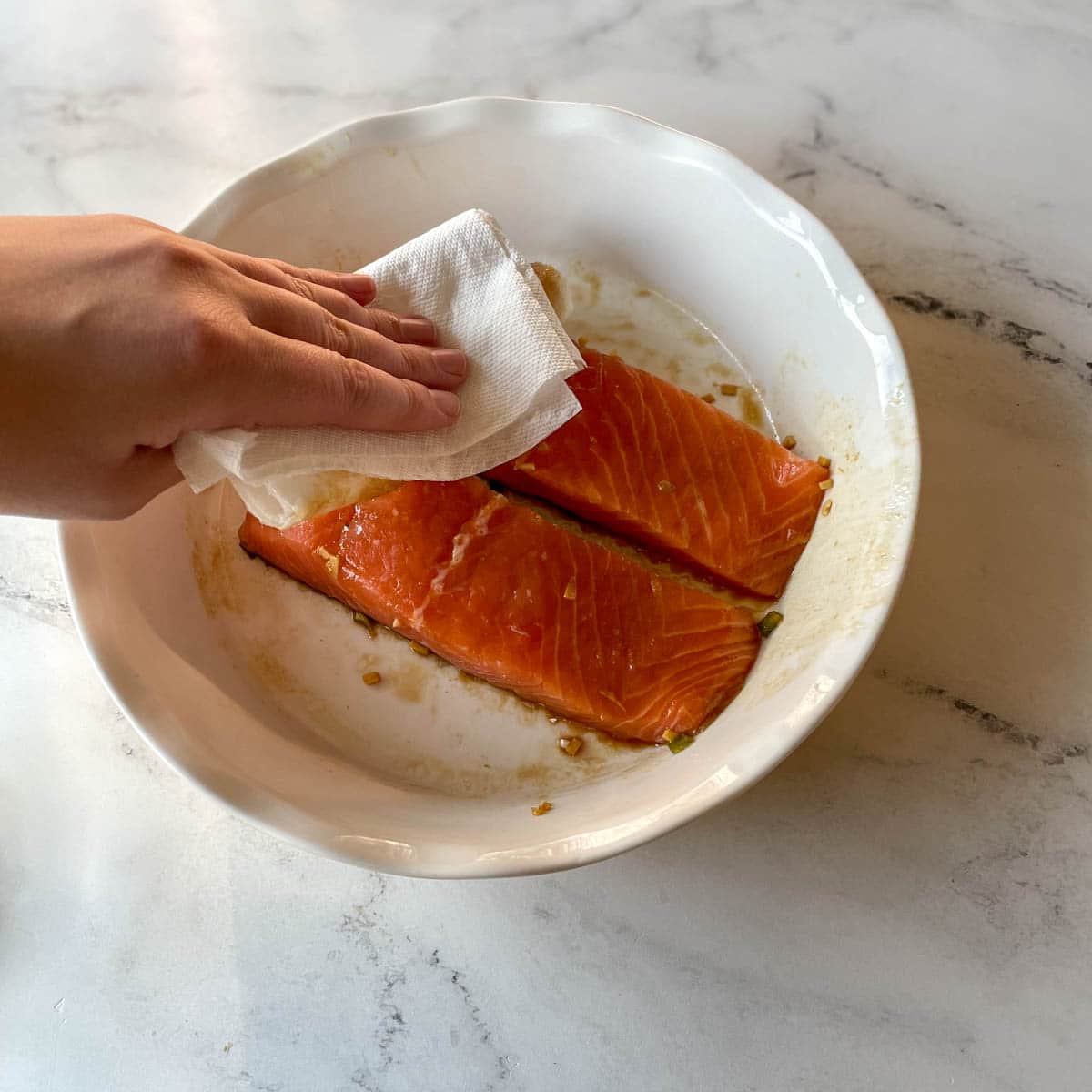 Two salmon fillets are blotted dry.