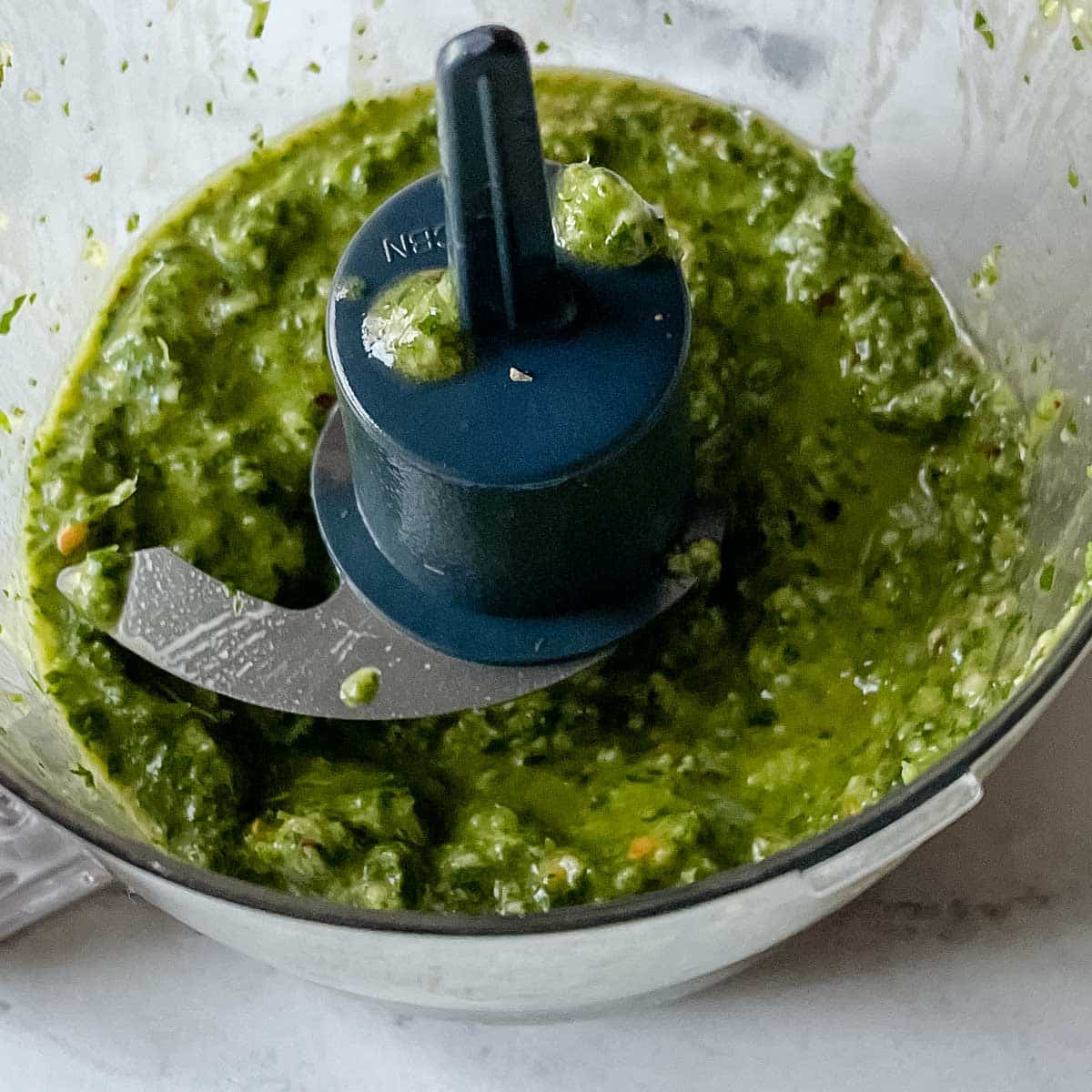 Blended chimichurri is shown in a mini food processor.