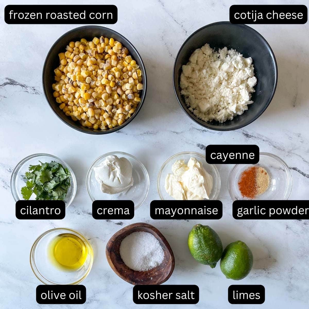 The labeled ingredients for esquites sit on a white marble counter.