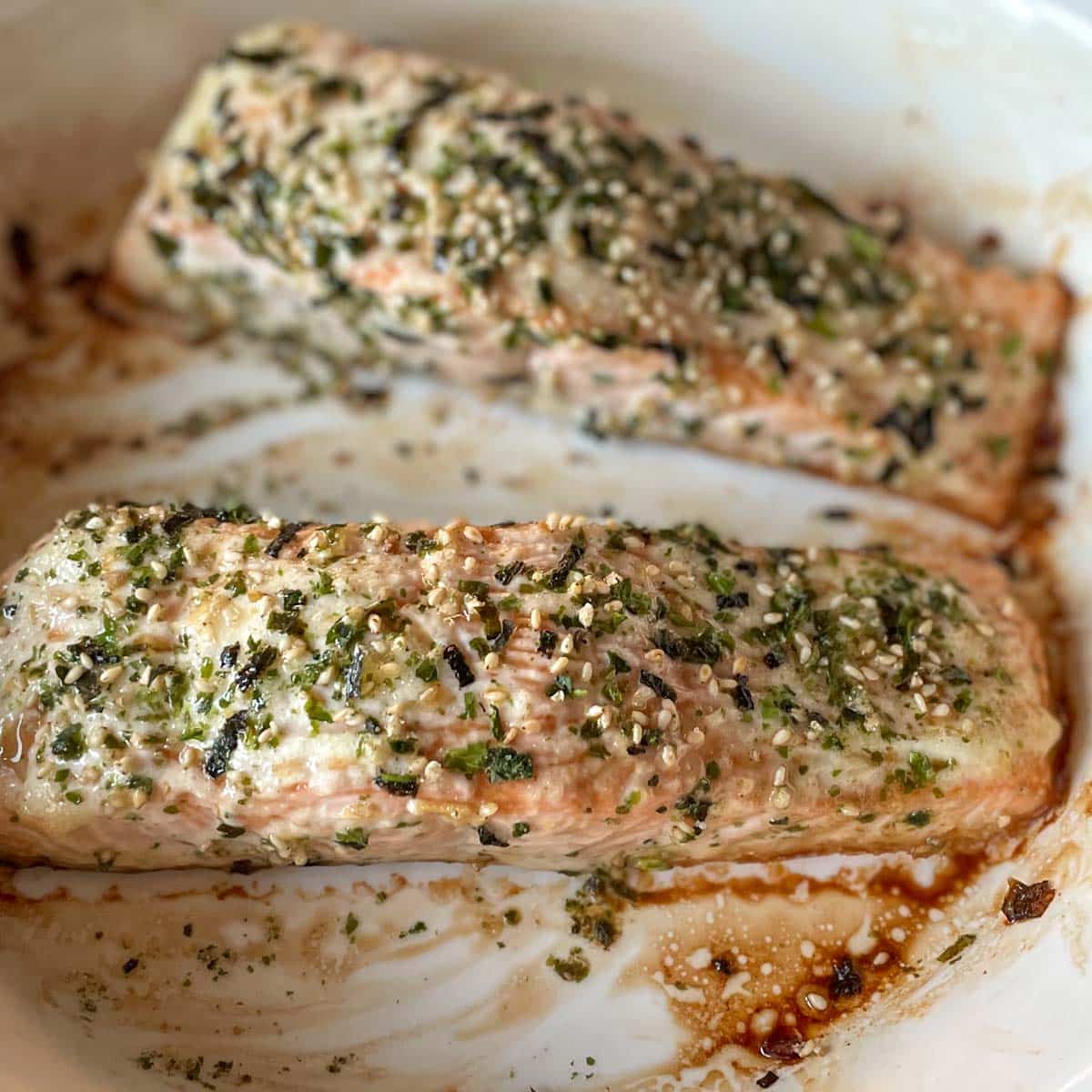 Baked salmon fillets coated in mayonnaise and furikake sit in a white baking dish.