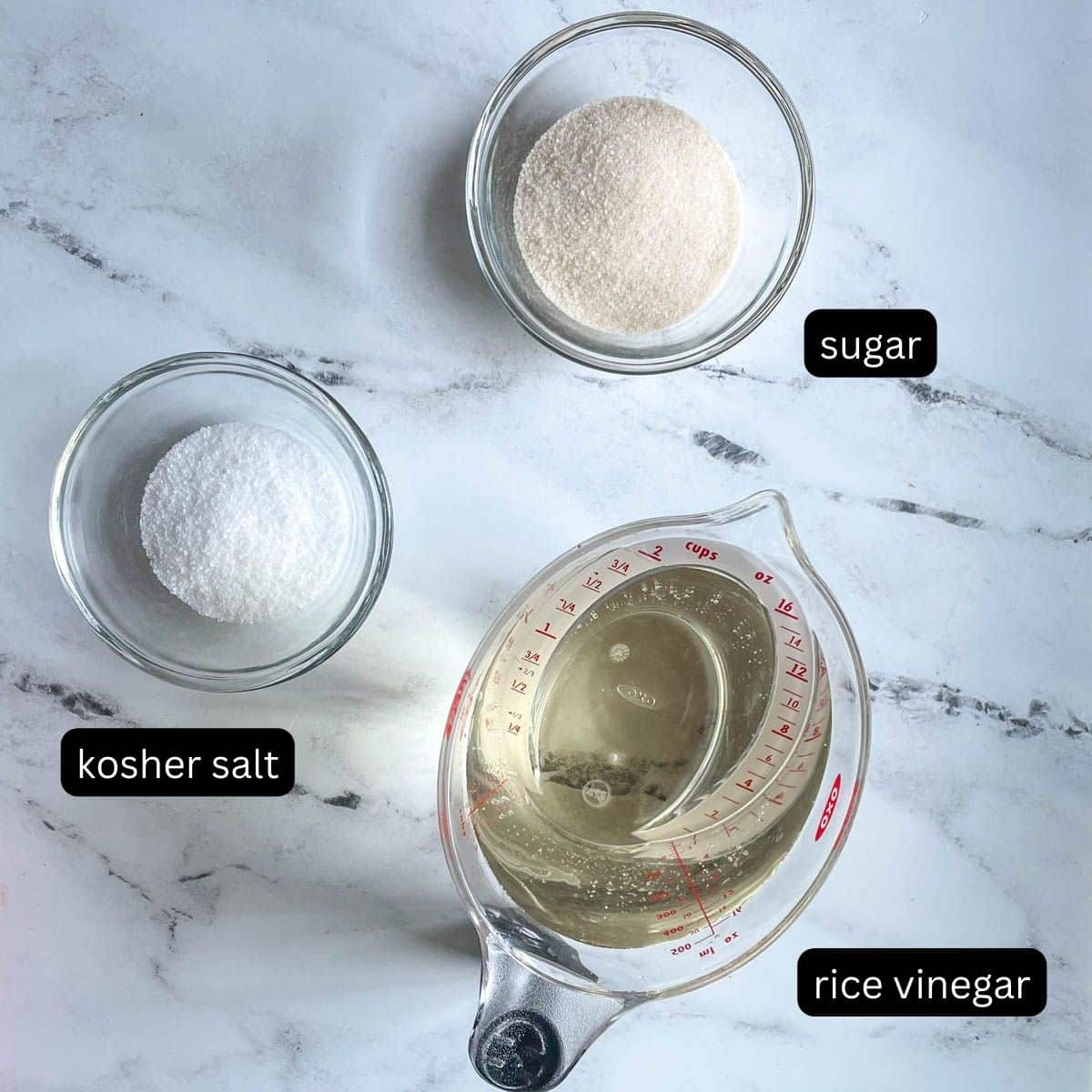 Kosher salt, sugar, and rice vinegar are shown on a white marble counter.