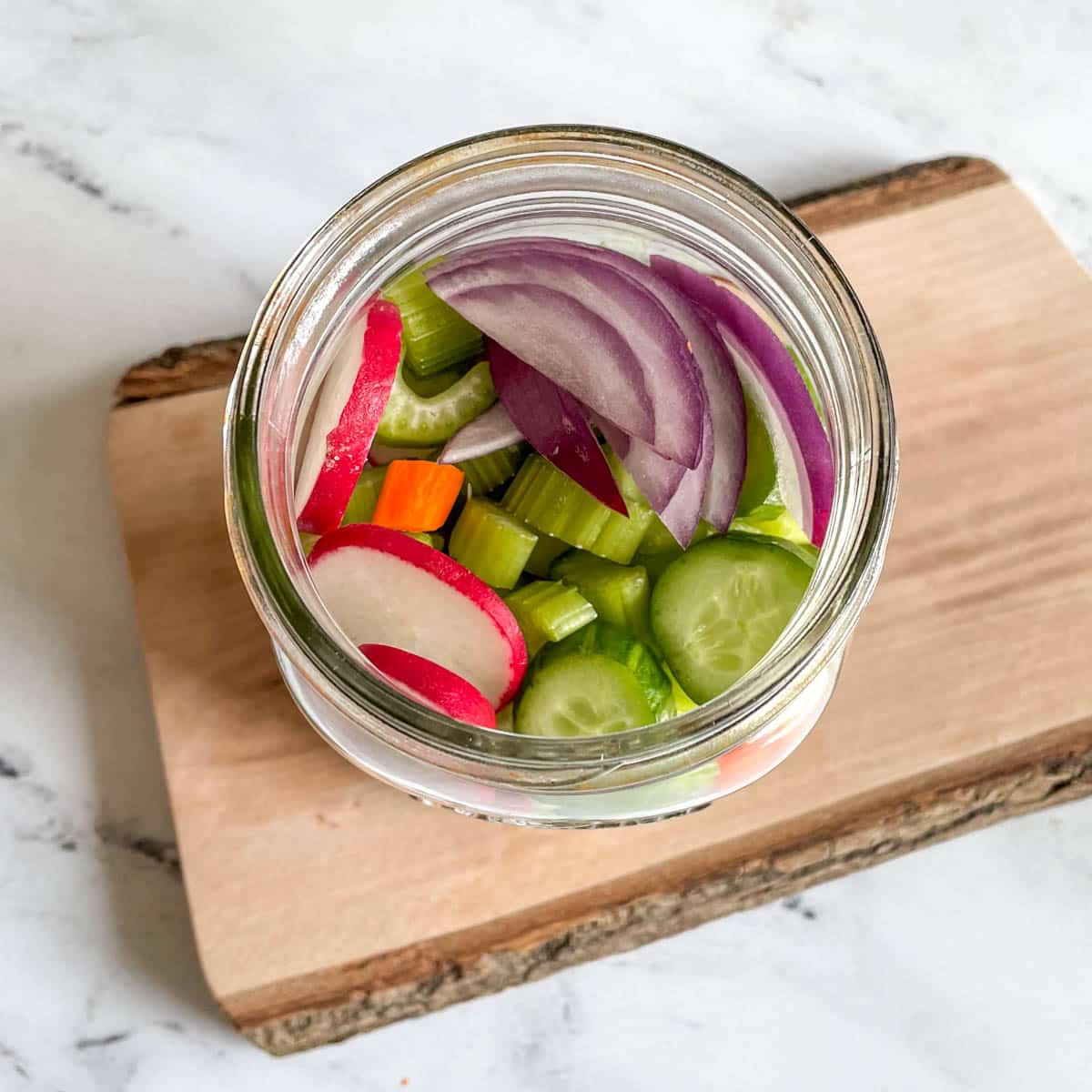 Mixed, cut vegetables are shown in a glass jar.