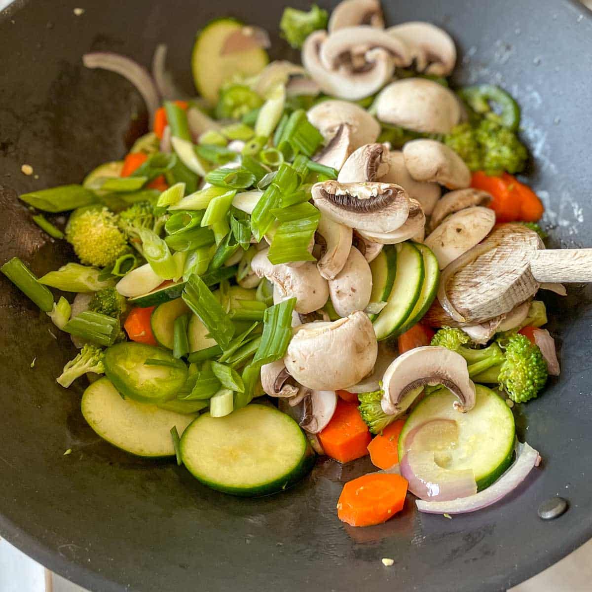 Mushrooms and scallions are added to the wok.