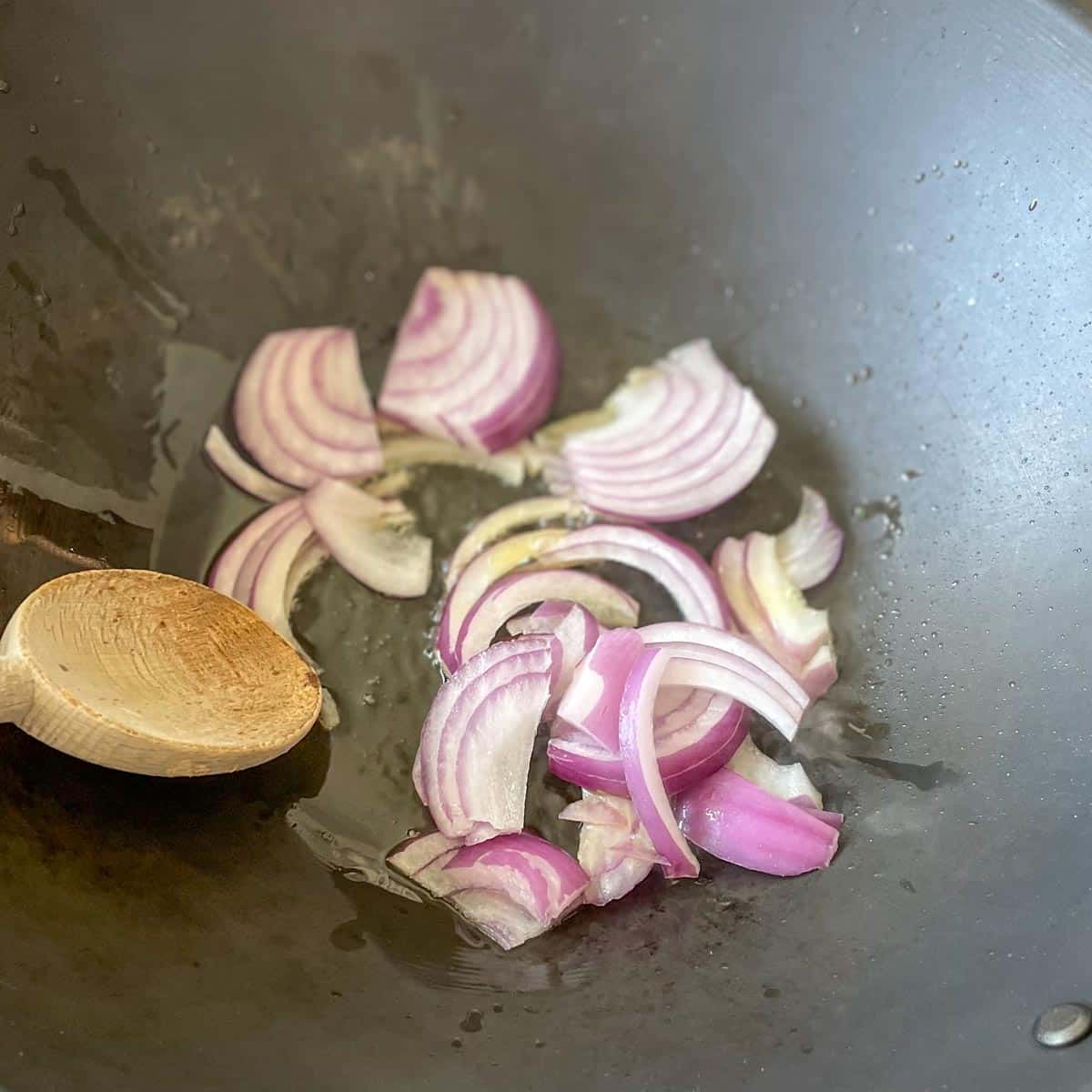 Onion is cooked in a wok.