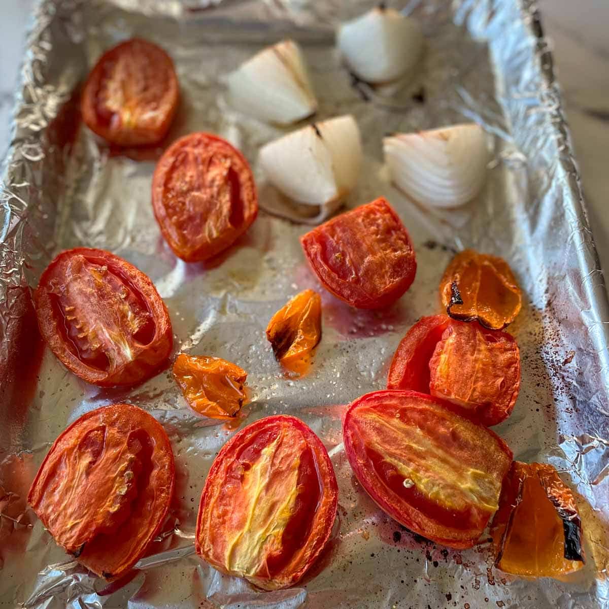 Roasted tomato, habanero, and onion are shown on a sheet tray.