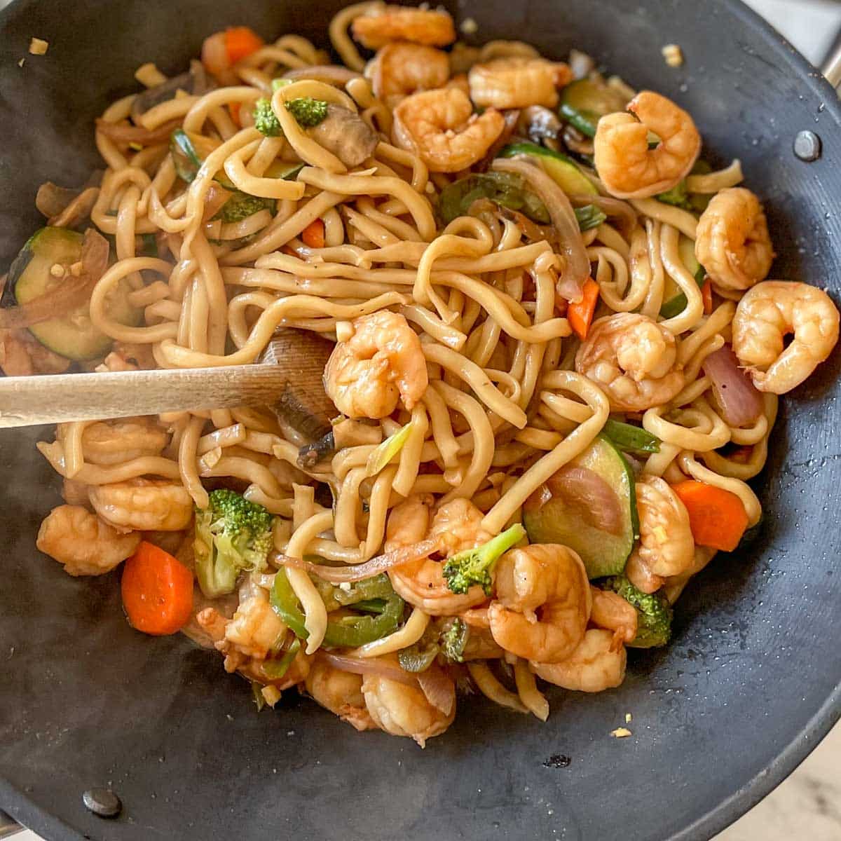 Shrimp is added back into the wok with noodles and vegetables.