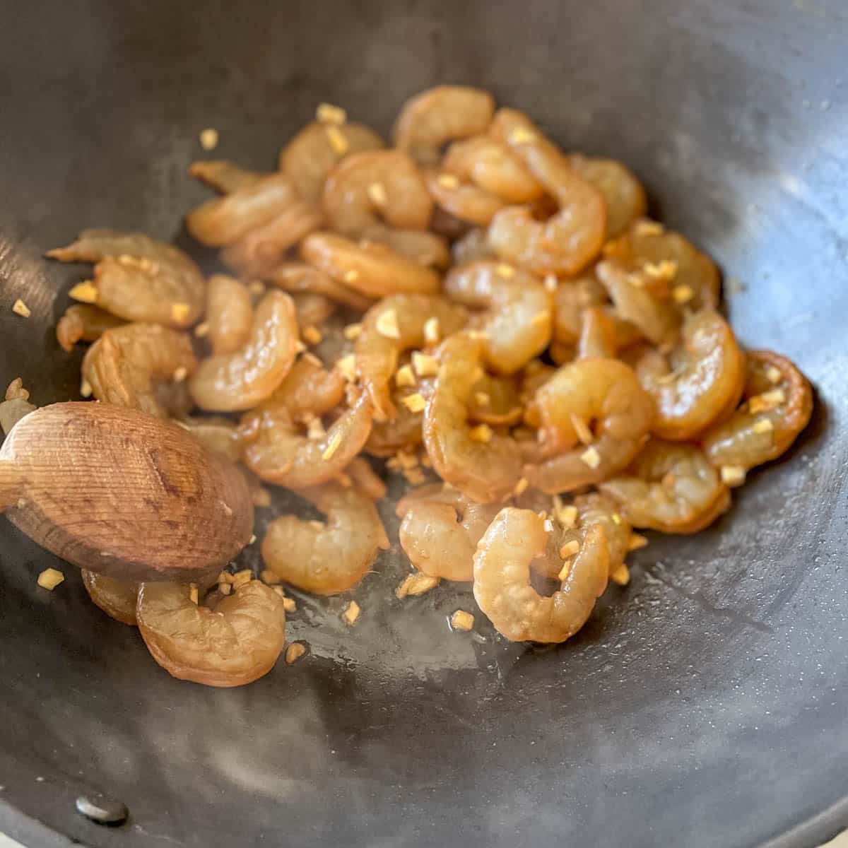 Marinated shrimp is cooked in a wok.