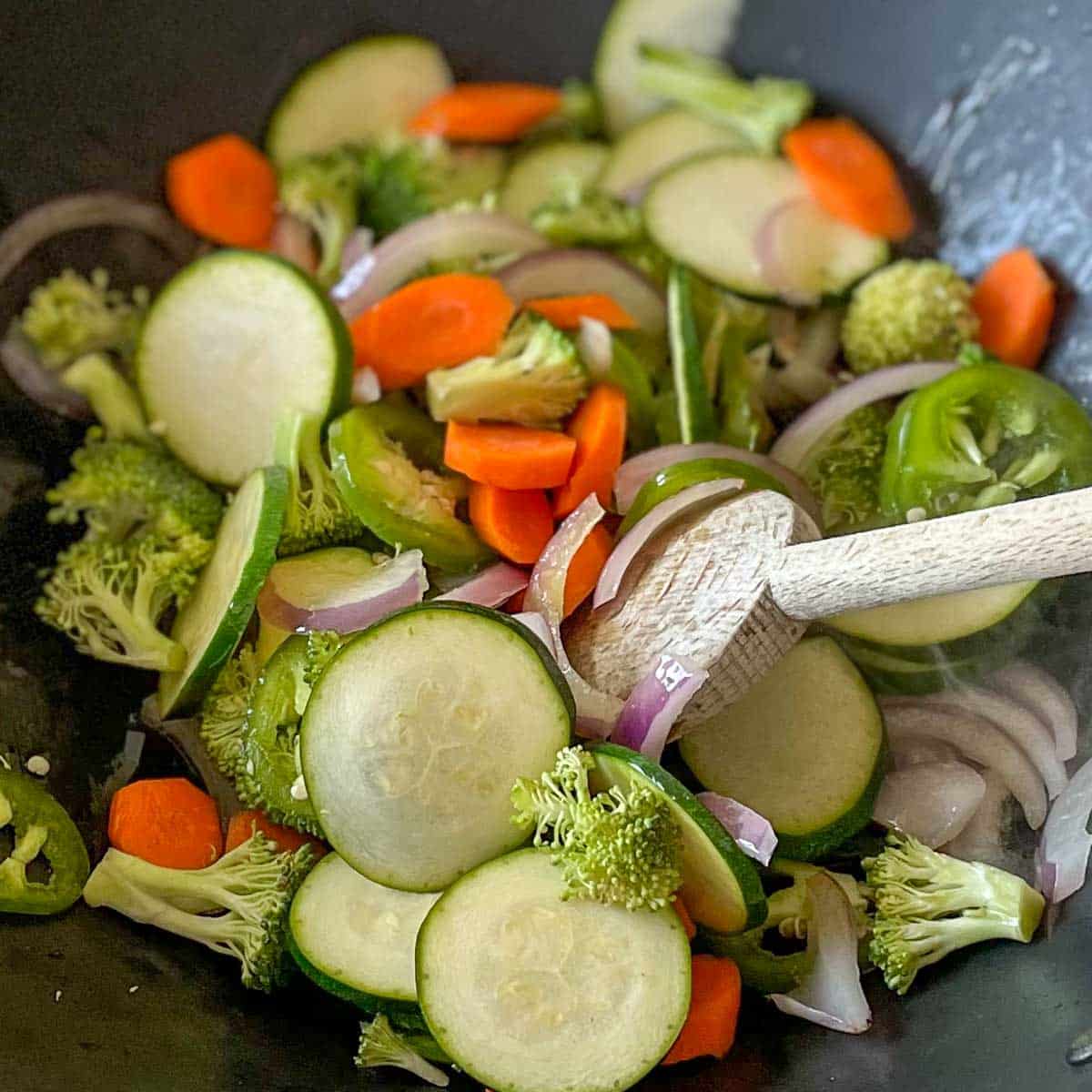 Zucchini, carrot, broccoli and jalapeño are added to the wok.