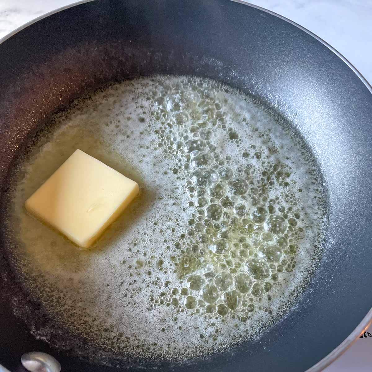 Butter is shown melting in a black nonstick pan.