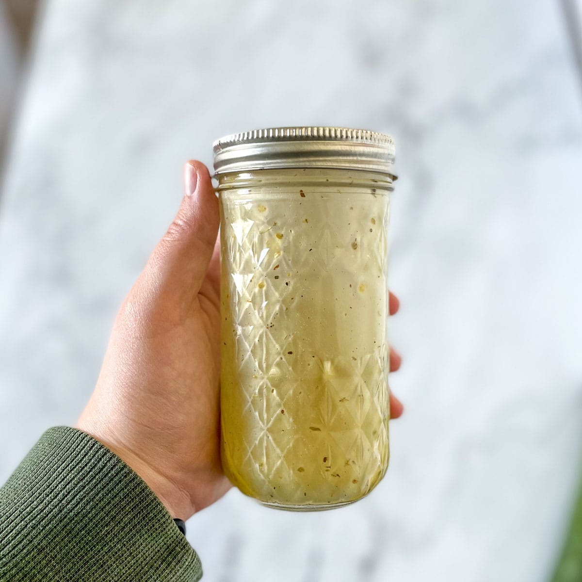 The emulsified vinaigrette is shown in a glass jar.