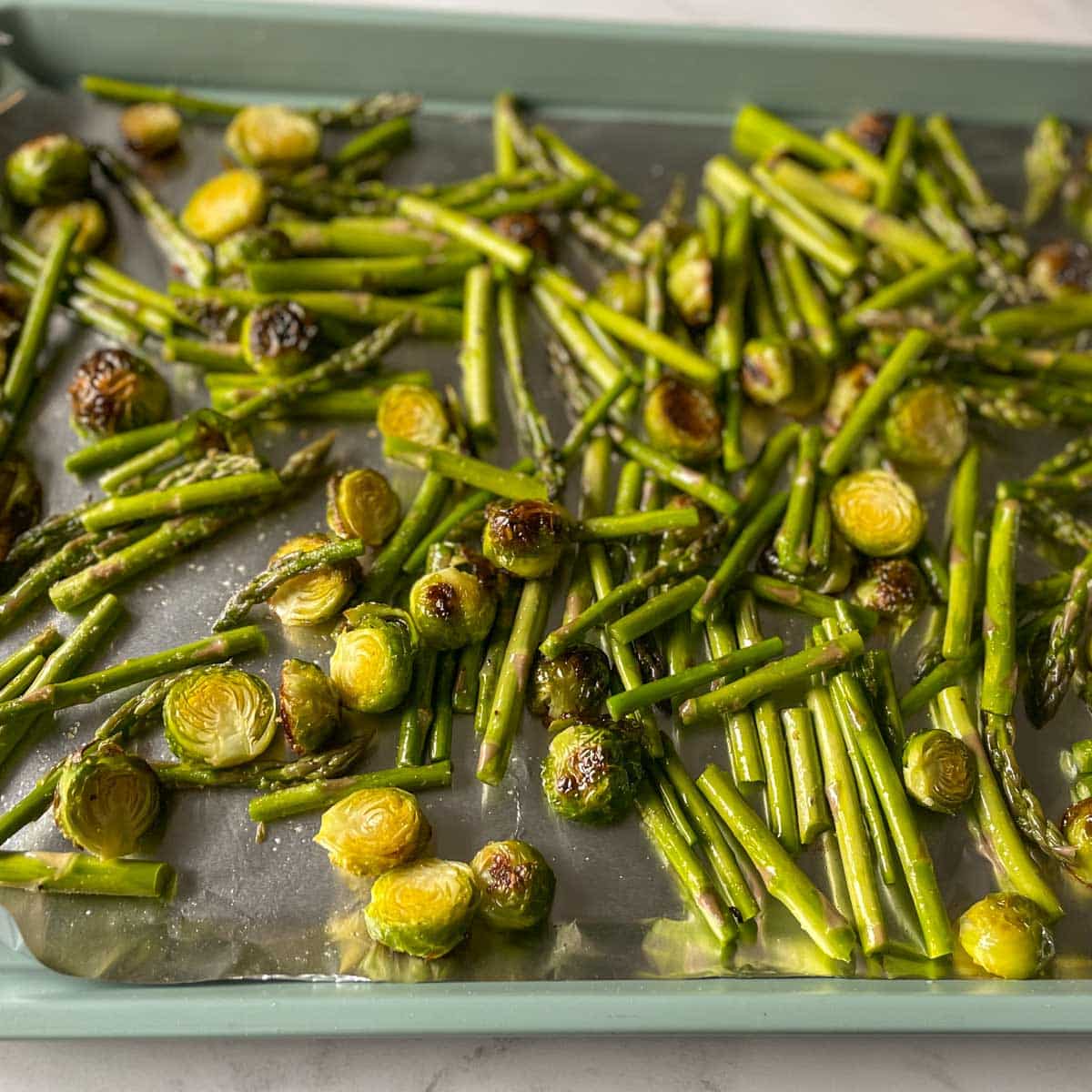 Asparagus is added to the sheet tray with the brussels sprouts.