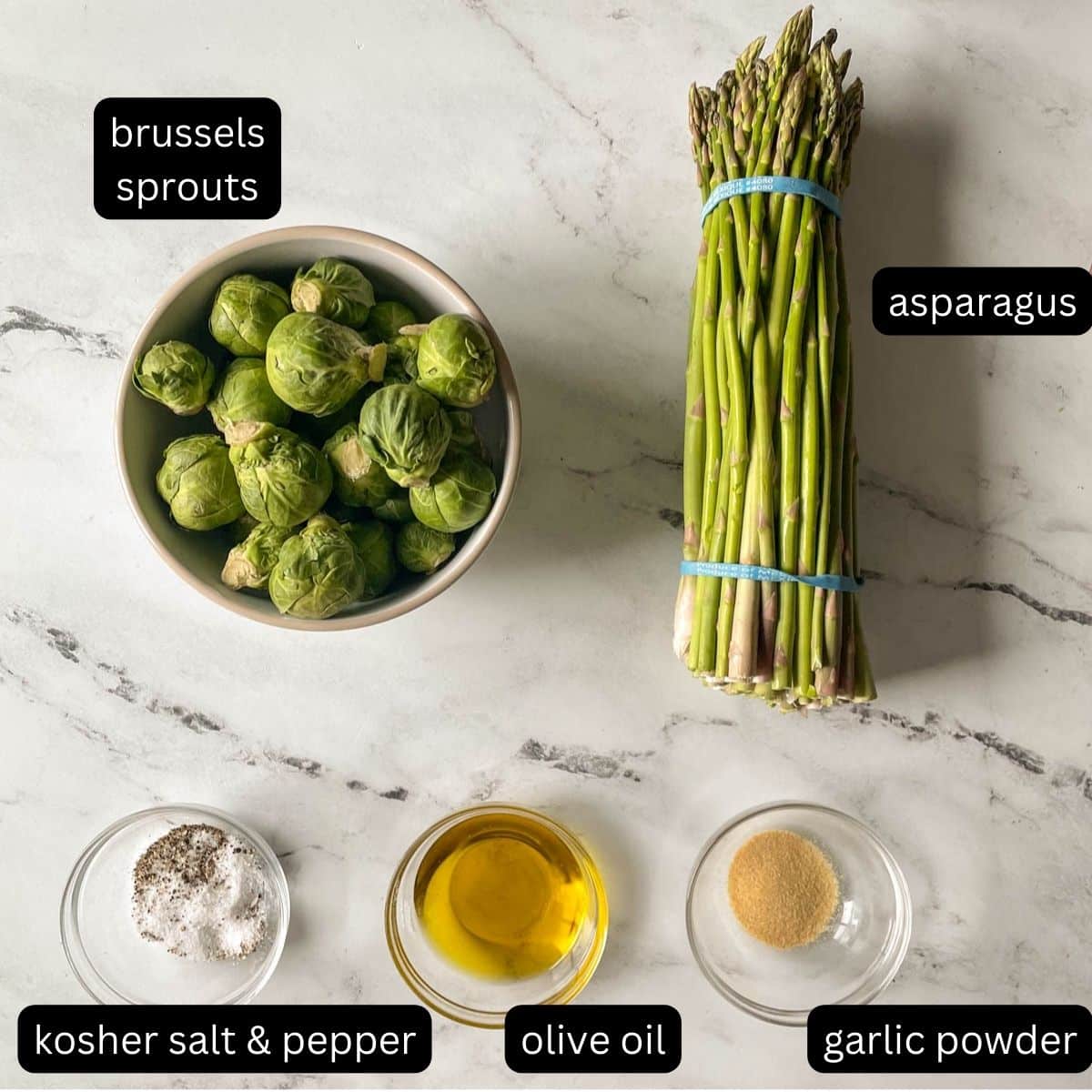 The labeled ingredients for brussels sprouts and asparagus sit on a white marble counter.