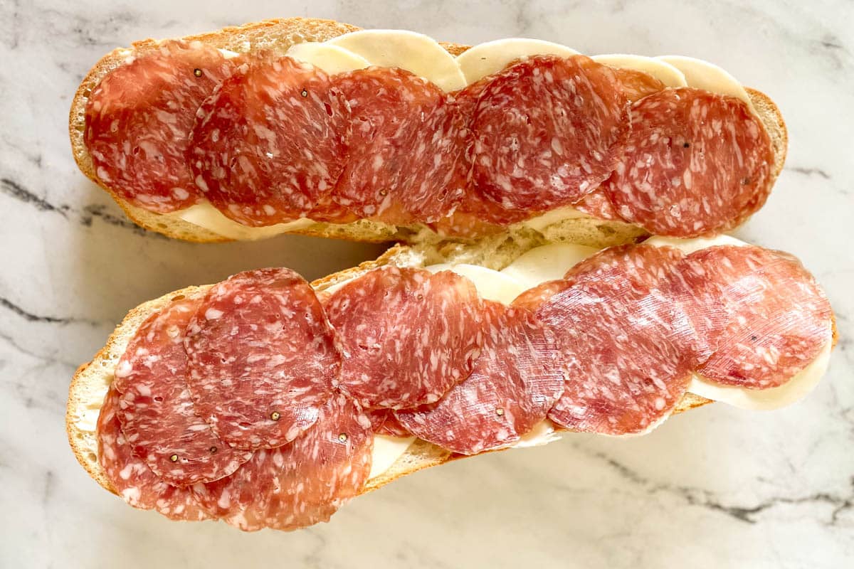 Salami is added to the grinder sandwich.