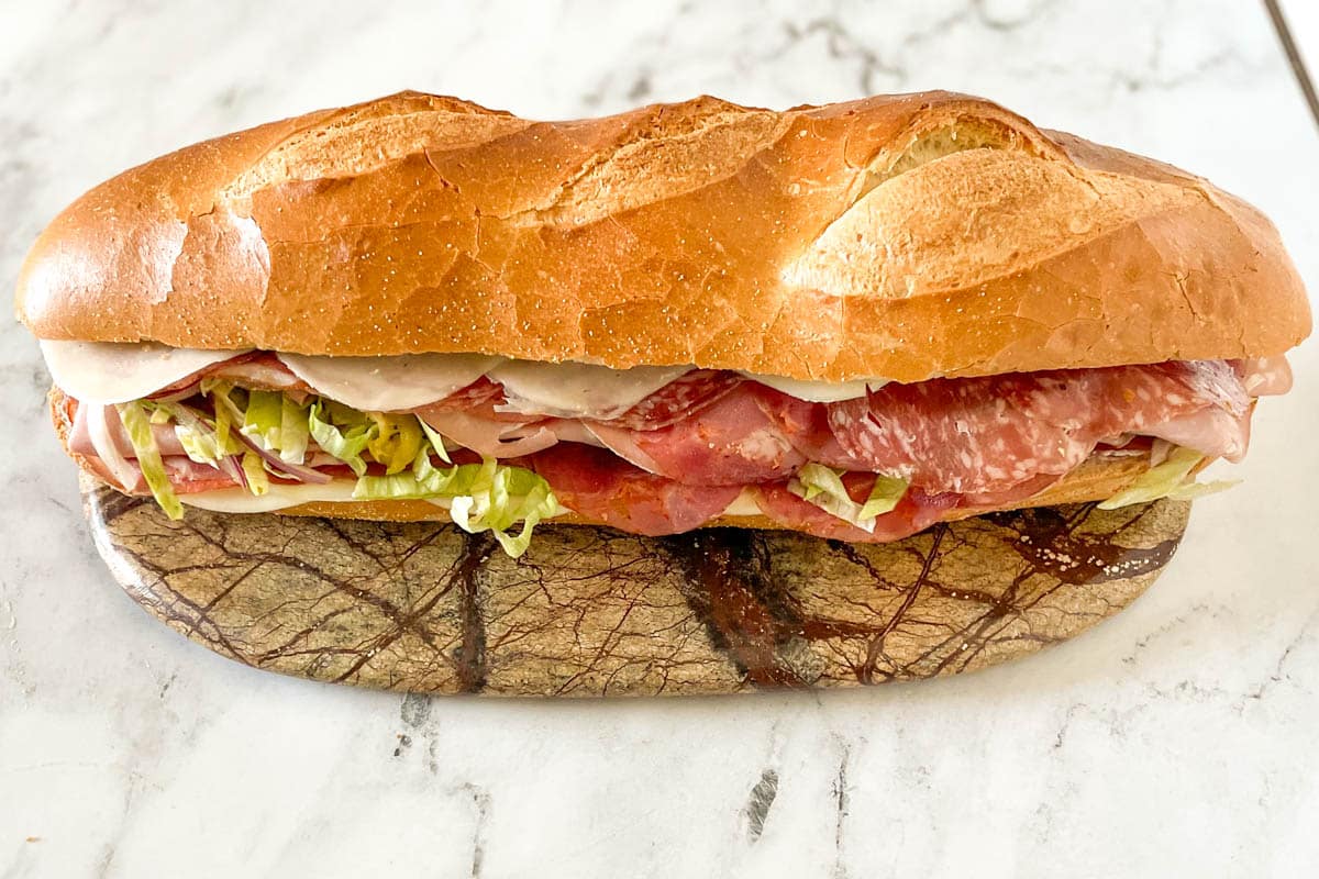 A finished grinder sandwich is shown on a marble platter.