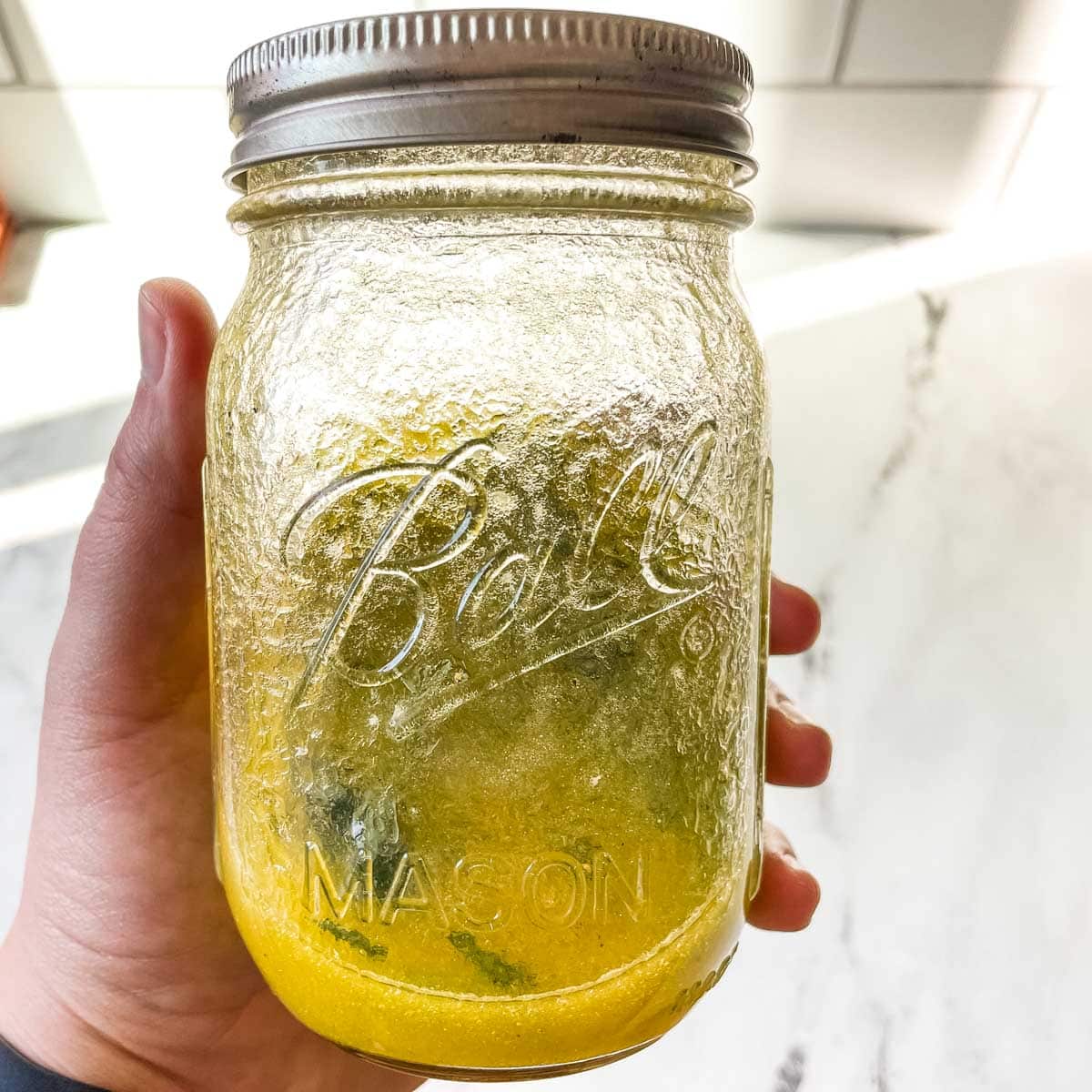 An emulsified lemon vinaigrette is shown in a glass jar.