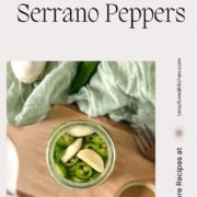A jar of pickled peppers and garlic is shown with the words Pickled Serrano Peppers and the URL www.twocloveskitchen.com.