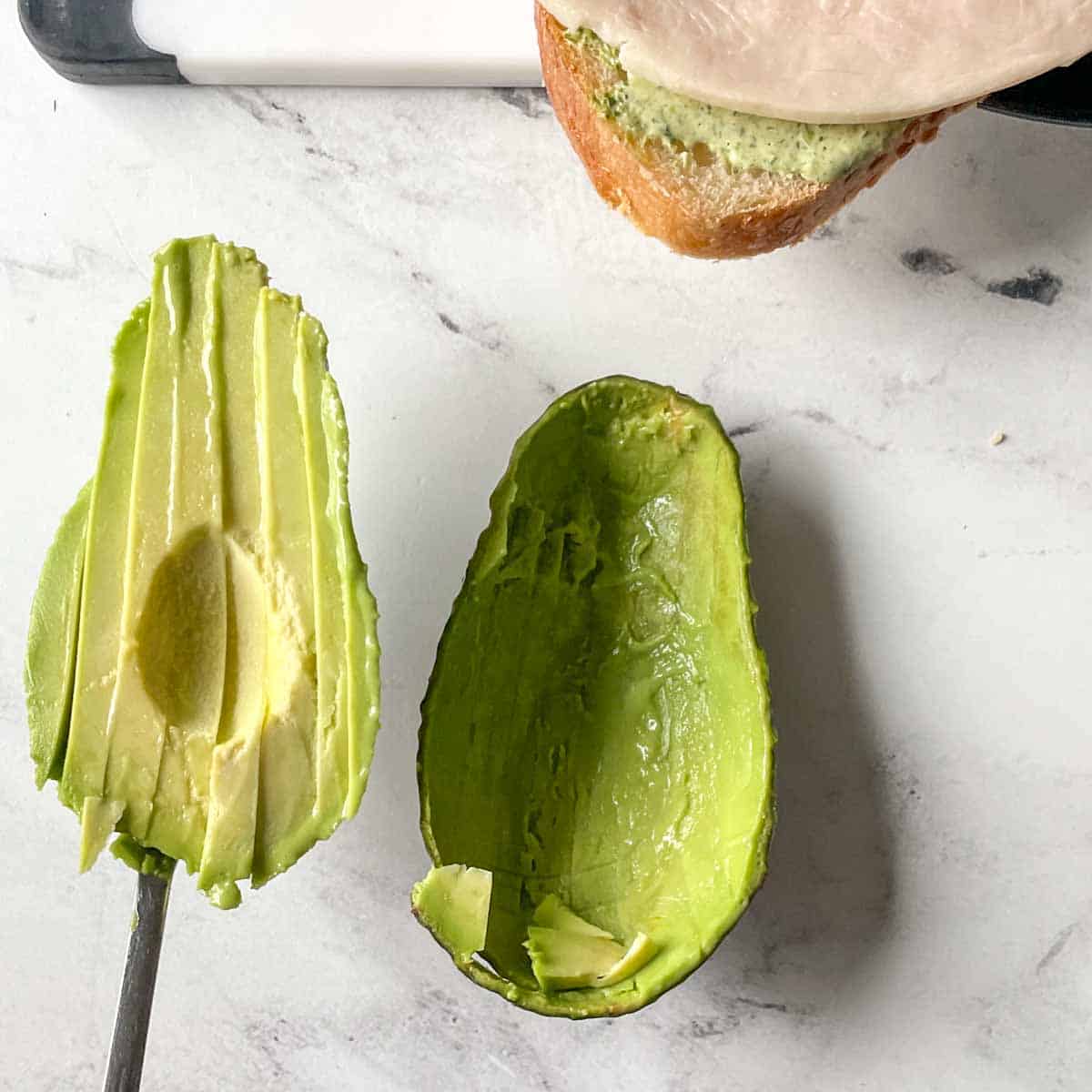 Thin slices of avocado are scooped out of their skin.