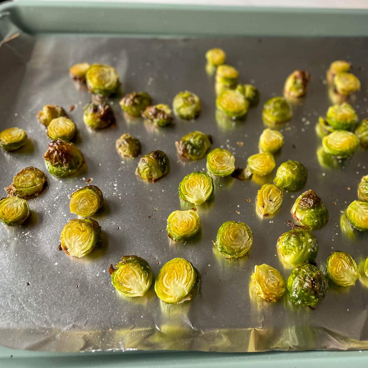 Roasted brussels sprouts are shown on a sheet tray.