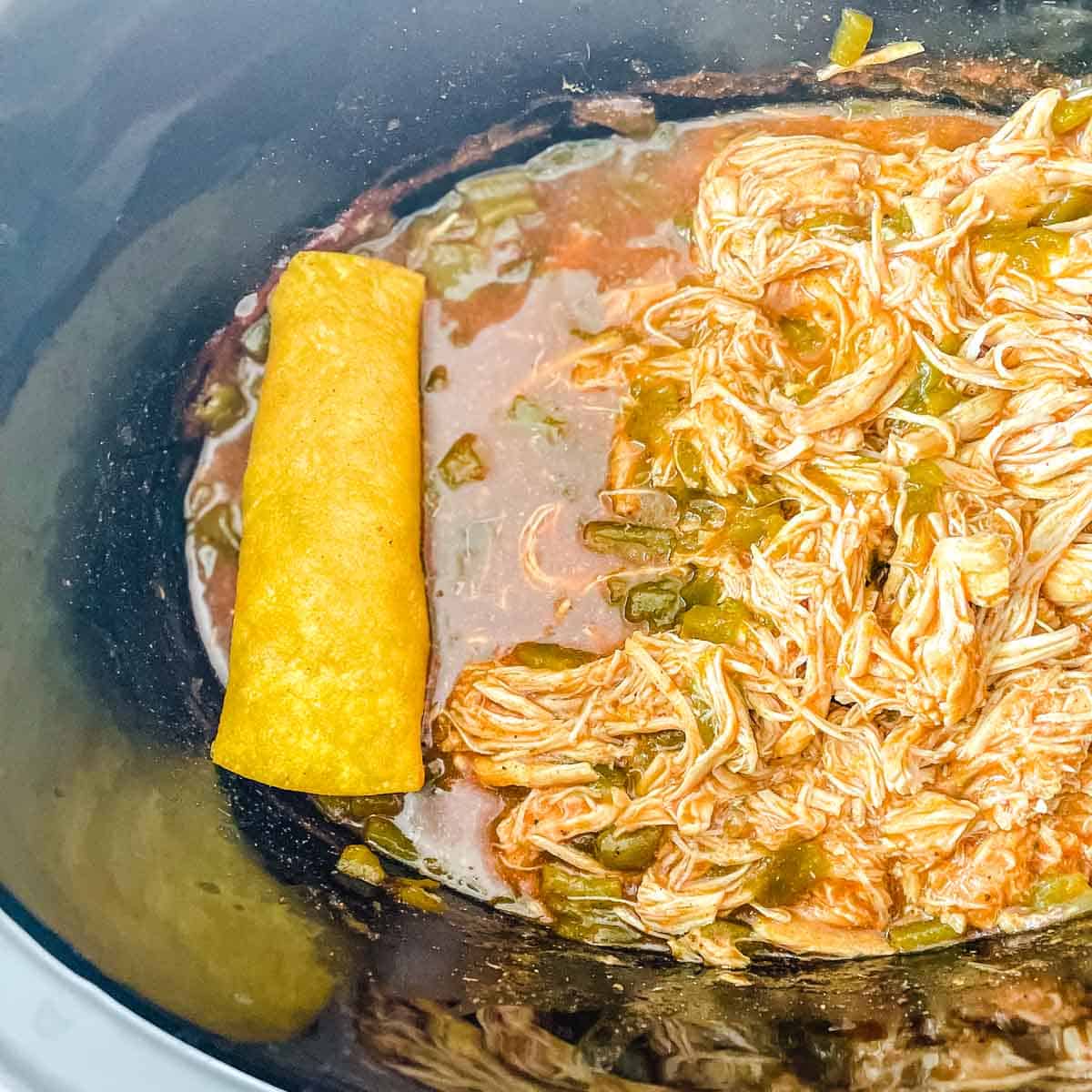 One chicken enchilada is added back to the crockpot.