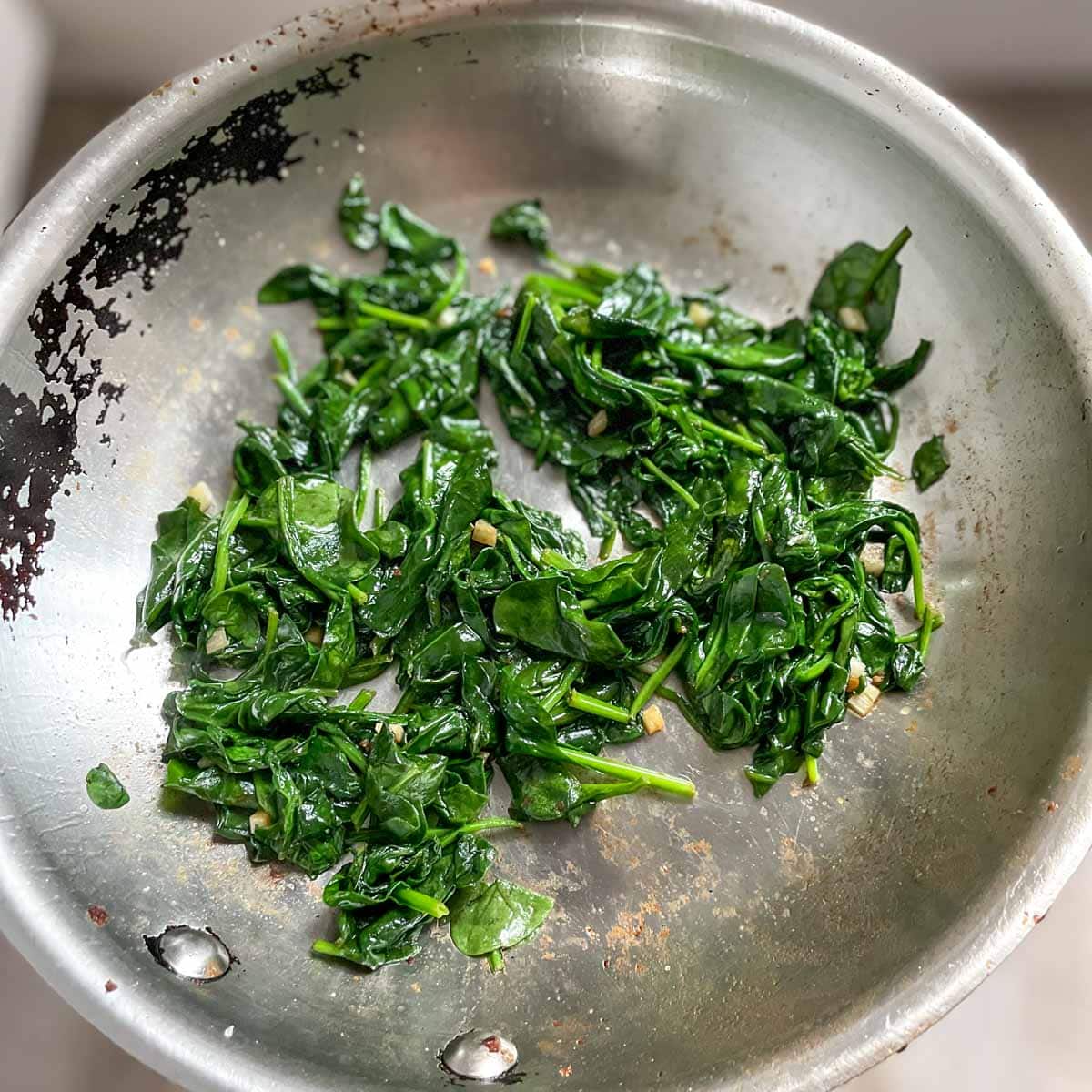 Sautéed spinach is shown in a pan.