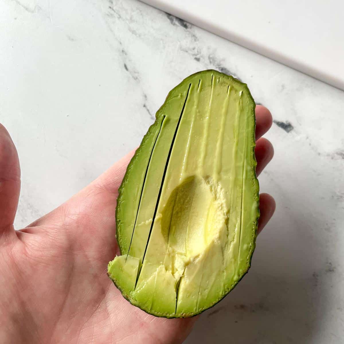 Half of an avocado is shown thinly sliced in its skin.