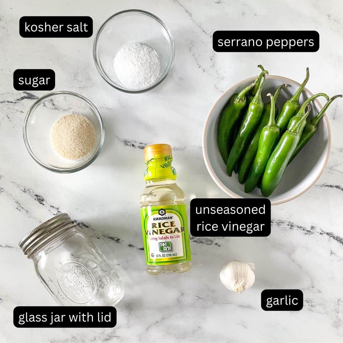 The labeled ingredients for pickled serrano peppers are shown on a white marble counter.
