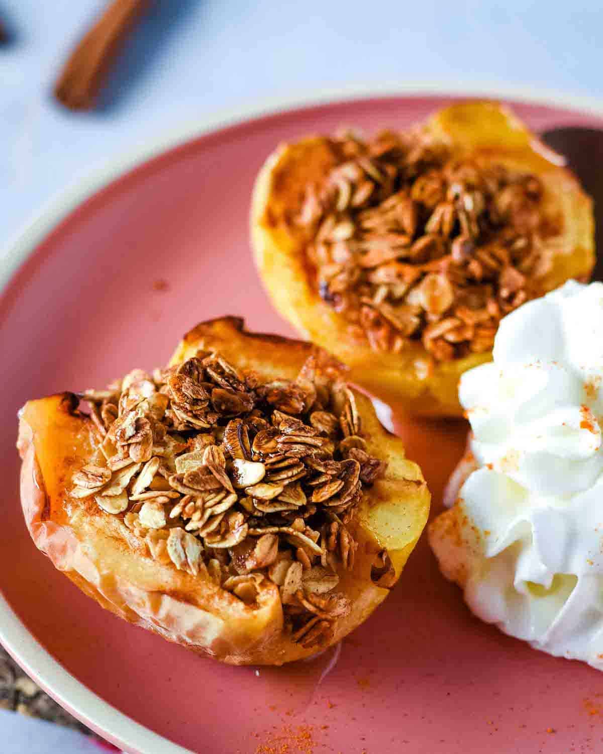Air fryer baked apples are shown on a pink plate with whipped cream.