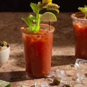 A virgin bloody mary is topped with olives, lime, cornichons, and celery.