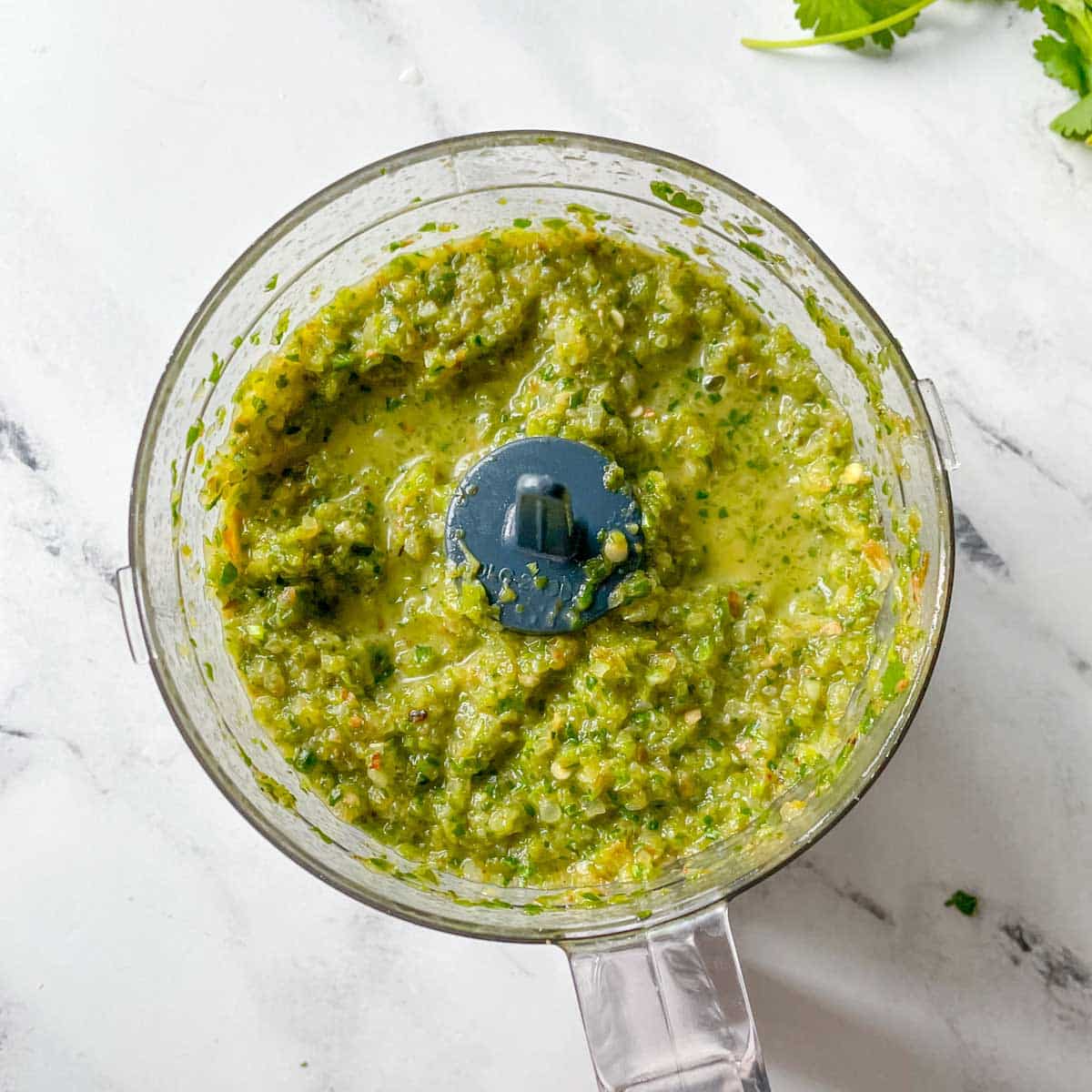 The finished serrano salsa is shown in the base of a food processor.