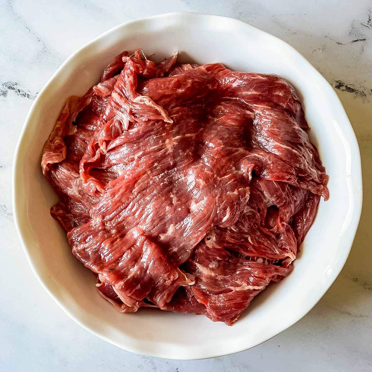 Flap steak is folded over itself in a white pie plate.