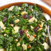 Kale salad is shown in a brown dish with a spoon.