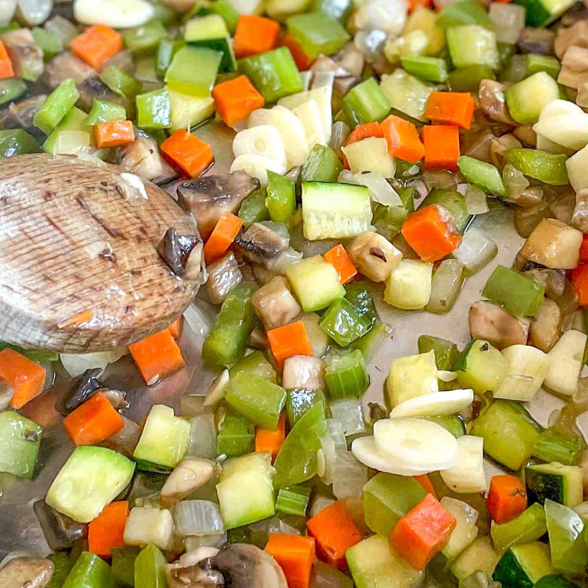 Garlic is added to the vegetables sweating in the pan.