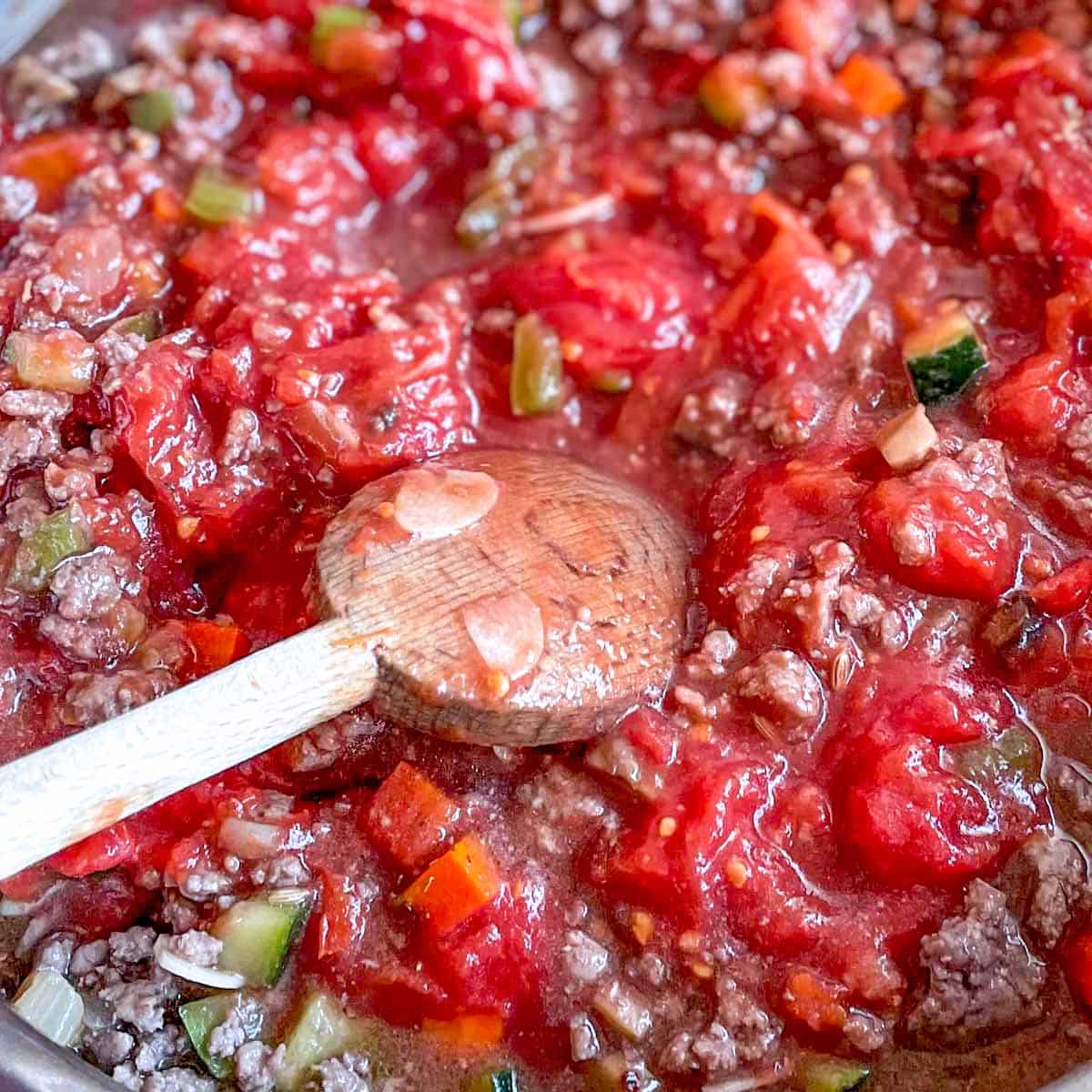 Crushed whole peeled tomatoes are added to the browned meat and vegetables.