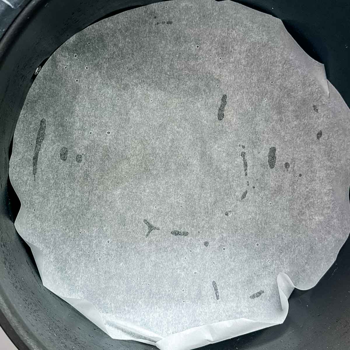 Parchment paper is shown in the base of an air fryer basket.
