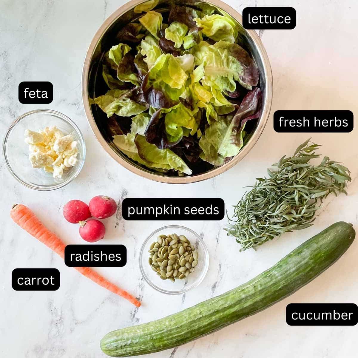 The labeled ingredients for a side salad are shown on a white marble counter.