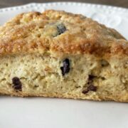 A closeup is shown of a sourdough chocolate chip scone on a white plate.