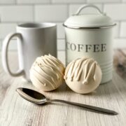 Two white mocha bombs sit on a white background with a container that says coffee.