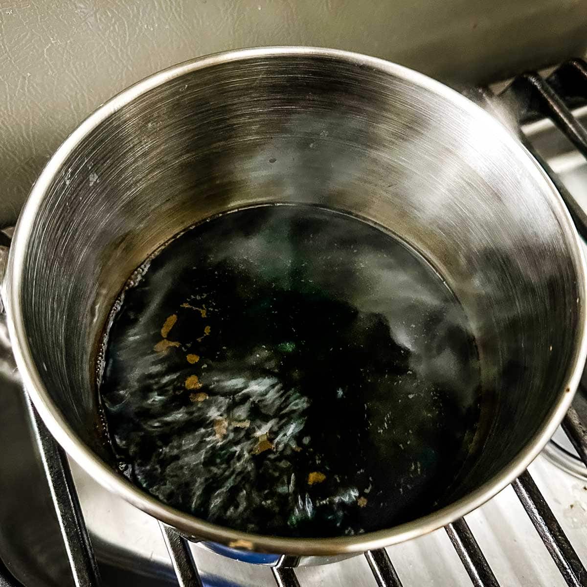 Balsamic vinegar reduces in a stainless steel pot.