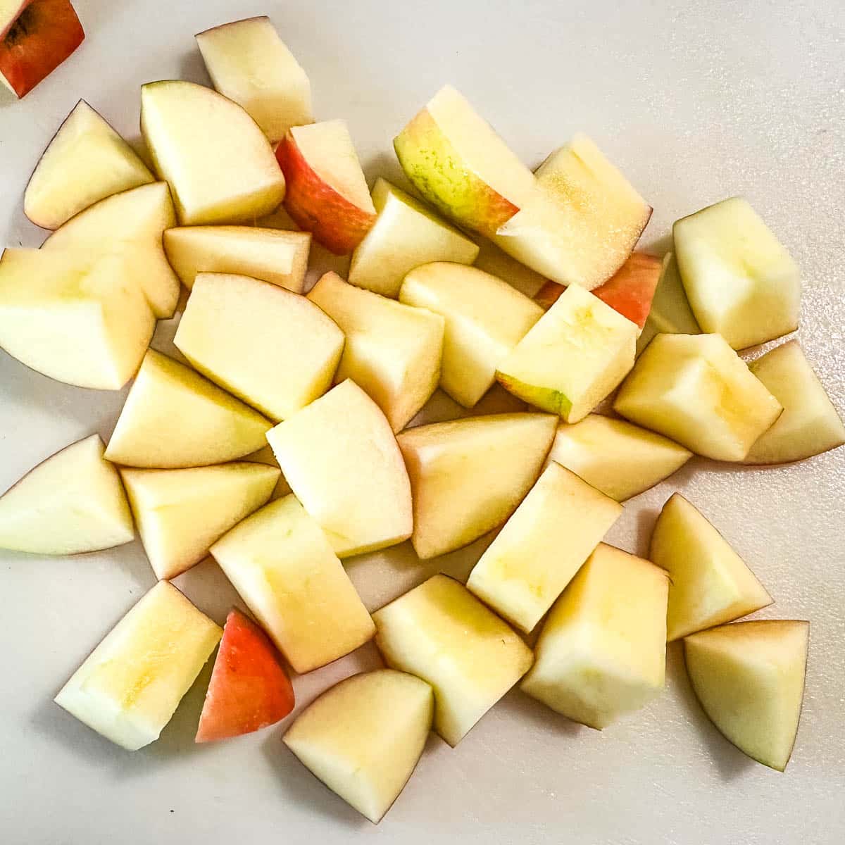 Sliced apples are chopped into bite-sized pieces.