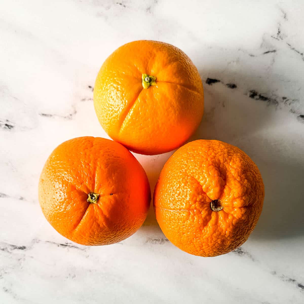 Fresh oranges on a white marble counter.