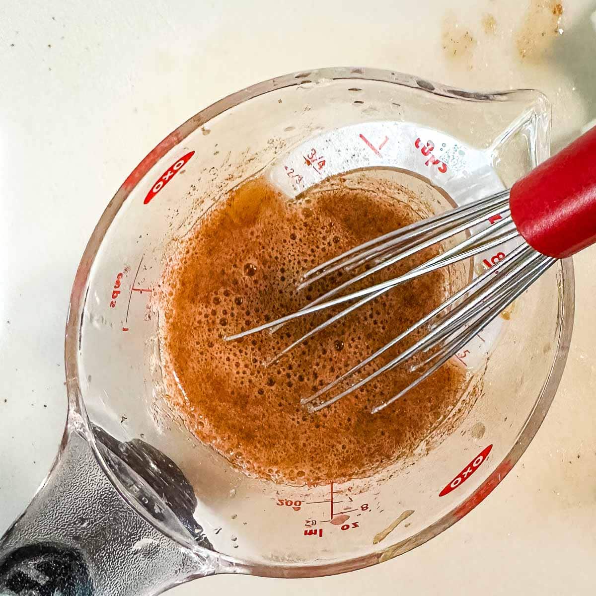 Honey, orange juice, and apple pie spice are mixed in a measuring cup.