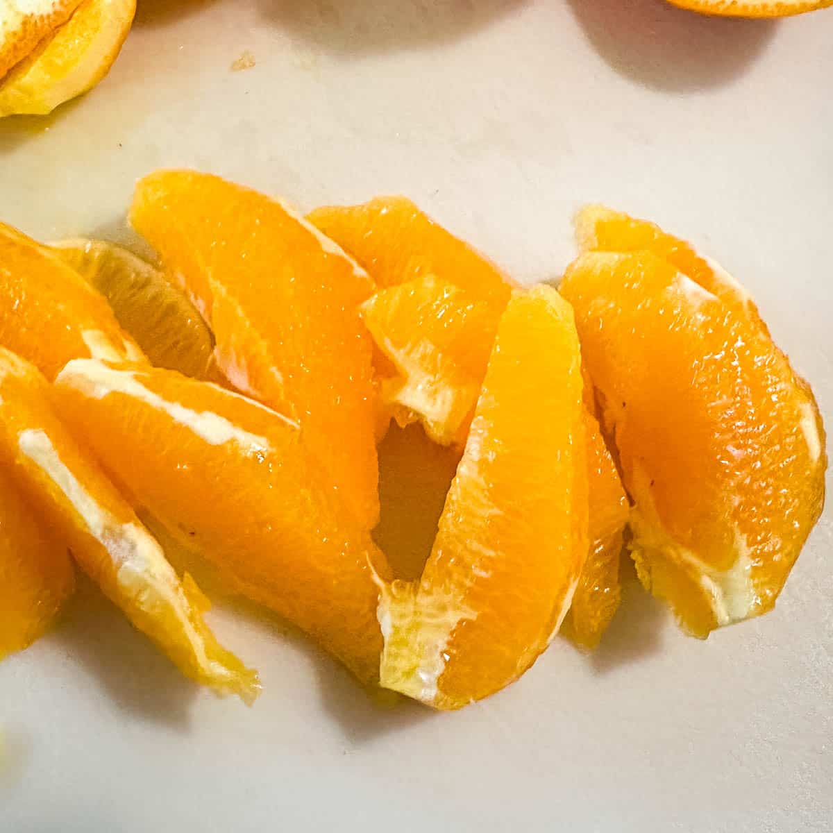 Orange segments on a white cutting board.