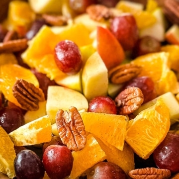 A closeup of Thanksgiving Fruit Salad with grapes, pears, apples, oranges, and pecans.