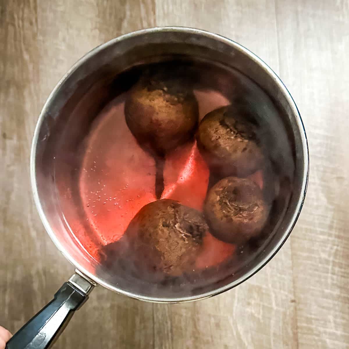 beets are placed in boiling water in a stainless steel pot.